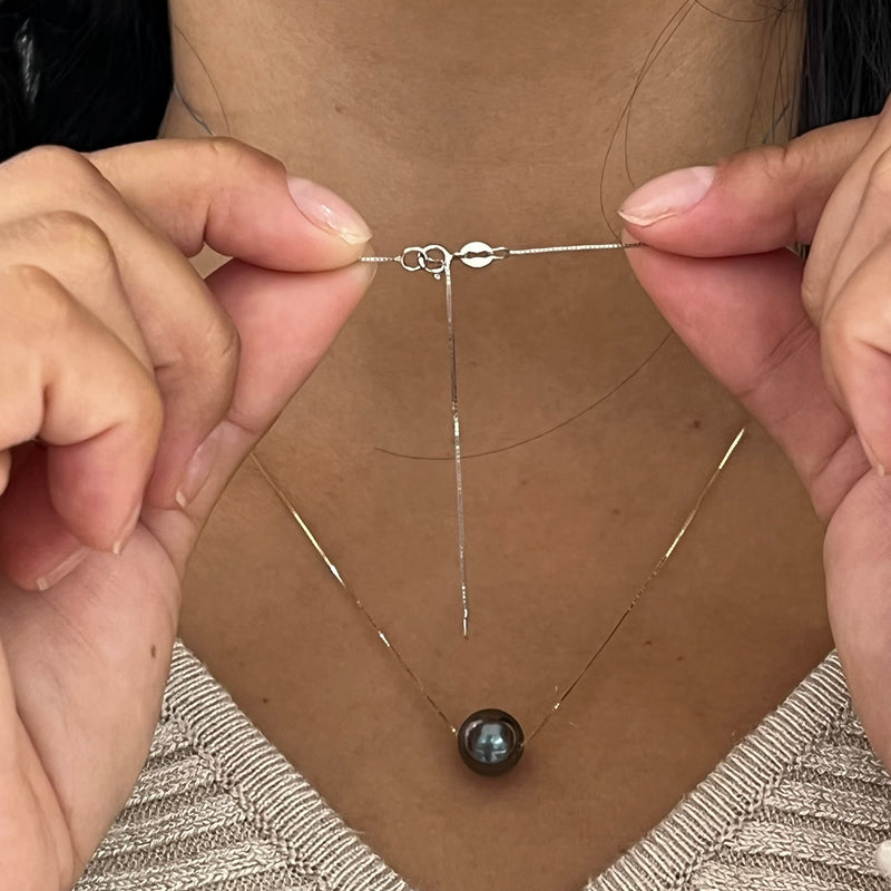 A woman showing the backing of the 16-18" Adjustable Tahitian Black Floating Pearl Necklace in White Gold-Maui Divers Jewelry